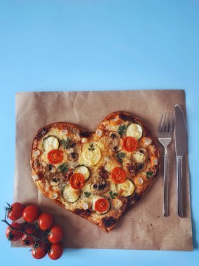 Lezzetli vejetaryen kalbi domatesli, sebzeli ve peynirli pizza. Mavi arka planda Sevgililer Günü için. Romantik aşkın yaratıcı yemek konsepti. Üst manzara, düz uzanma.