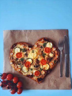 Lezzetli vejetaryen kalbi domatesli, sebzeli ve peynirli pizza. Mavi arka planda Sevgililer Günü için. Romantik aşkın yaratıcı yemek konsepti. Üst manzara, düz uzanma.