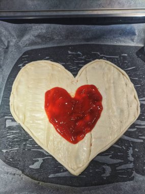 Sevgililer Günü tatili için bir pizza kalbi. Klasik İtalyan pizzasının evde yaptığı düz bir yatak. Sevgililer Günü yemeklerinin yaratıcı fikirleri.  