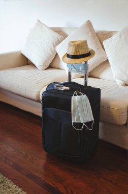 Karantina bittikten sonra yolculuk hazırlıkları. Salgından sonra yeni bir yaşam ve koronavirüsü (COVID-19) önleme kavramı. Tıbbi maske, eldiven, dezenfektan, güneş gözlüğü ve plaj şapkası bagajda.