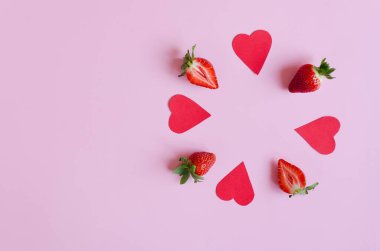 Şenlikli pembe arka plan. Kırmızı kağıt kalpler ve taze çilekler. Sevgi. Sevgililer Günü. 14 Şubat. Yaratıcı tebrik kartı. Düz yatış, üst görünüm.