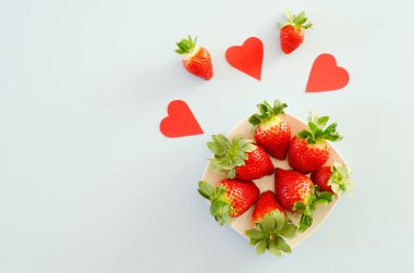 Neşeli mavi arka plan. Kırmızı kağıt kalpler ve taze çilekler. Sevgi. Sevgililer Günü. Sağlıklı yemek geçmişi. Yaratıcı tebrik kartı. Düz yatış, üst görünüm.