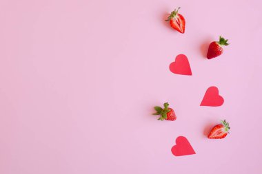 Şenlikli pembe arka plan. Kırmızı kağıt kalpler ve taze çilekler. Sevgi. Sevgililer Günü. 14 Şubat. Yaratıcı tebrik kartı. Düz yatış, üst görünüm.