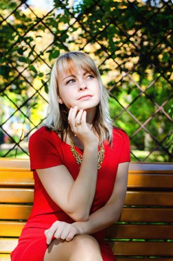 Sonbahar parkında kırmızı elbiseli, sarı saçlı zarif bir kadının portresi.. 