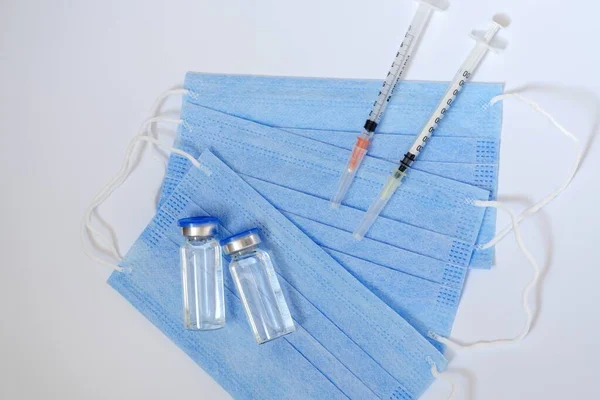 予防接種の概念の創造的なアイデア Covid 19ワクチン接種用の医療用マスクとワクチン瓶付き注射器のトップビュー コロナウイルスのパンデミック スペースのコピー — ストック写真