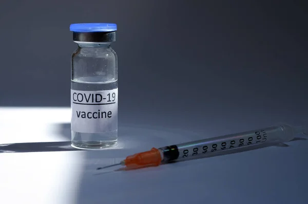 Creative ideas of vaccination concept. Top view of medical masks and vaccine vial glass bottles for vaccination against COVID-19. Coronavirus pandemic. Copy space.