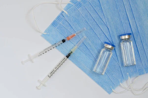 予防接種の概念の創造的なアイデア Covid 19ワクチン接種用の医療用マスクとワクチン瓶付き注射器のトップビュー コロナウイルスのパンデミック スペースのコピー — ストック写真