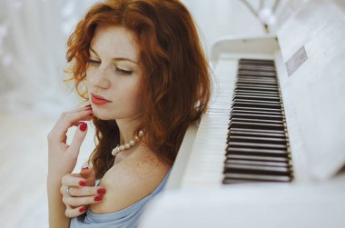 Güzel kızıl saçlı, mavi gözlü ve çilli genç bayan piyanist stüdyoda bir piyanonun yanında oturuyor ve müzik öğreniyor. Müzik yapmanın yaratıcı süreci.