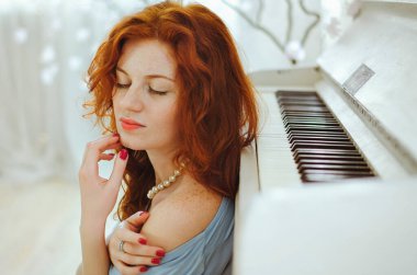 Güzel kızıl saçlı, mavi gözlü ve çilli genç bayan piyanist stüdyoda bir piyanonun yanında oturuyor ve müzik öğreniyor. Müzik yapmanın yaratıcı süreci.