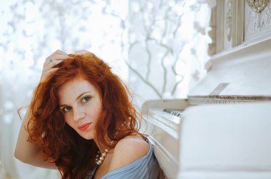 Güzel kızıl saçlı, mavi gözlü ve çilli genç bayan piyanist stüdyoda bir piyanonun yanında oturuyor ve müzik öğreniyor. Müzik yapmanın yaratıcı süreci.