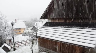 Köyün üzerindeki kar manzarası ve kışın soğuk bir günde yolu kaplayan kar manzarası. Bohinj, Slovenya. 