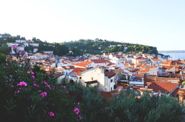 Eski şehir Piran 'ın tarihi merkezinin kırmızı çatılarının manzarası. Gündoğumunda gökyüzüne ve mavi Adriyatik denizine karşı ana kilise. Hava manzaralı, Slovenya kıyısı. 