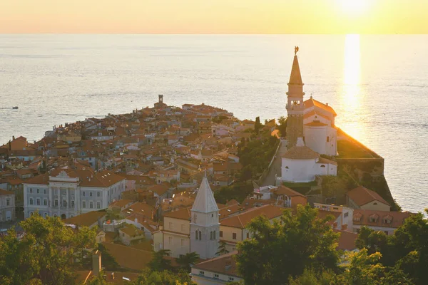 日の出の空と青いアドリア海に対するメイン教会と旧市街ピランの歴史的中心部の赤い屋根の風景 空中ビュー スロベニアの海岸 — ストック写真