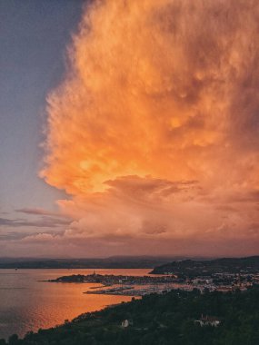Scenic view to the amazing red sunset at the Adriatic sea, coast in Slovenia at summer. View to green hills with palms and olive trees. Natural backgrounds. 
