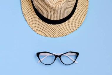 Güneş gözlüğü, saman kayıkçı şapkası ve mavi arka planda parlak sarı ayçiçeğiyle yatıyordu. Seyahat yaz konsepti. Boşluğu kopyala. 
