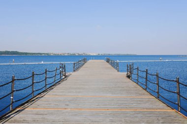 Güneşli bir günde kumsalın yanındaki mavi gökyüzüne karşı rıhtım. Slovenya 'da Adriyatik kıyısı ve denizi. Tatil ve seyahat kavramı. 
