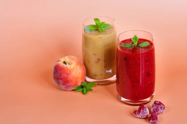 Top view of different fresh delicious smoothies in a glasses made of peach, banana and berries with mint. Creative concept of healthy detox drink, diet or vegetarian food concept. Copy space.