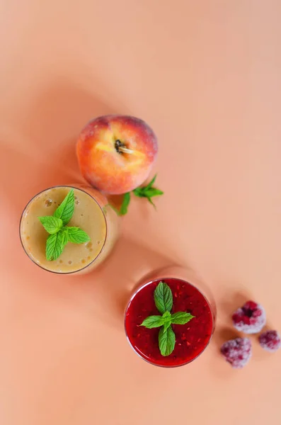 Top view of different fresh delicious smoothies in a glasses made of peach, banana and berries with mint. Creative concept of healthy detox drink, diet or vegetarian food concept. Copy space.