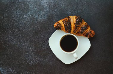 İş adamı sabah not defteri, bir fincan sıcak kahve ve siyah arka planda tatlı kruvasanla çalışıyor. Üst görünüm, kopyalama alanı, modelleme. Düz yatıyordu. Modern kahvaltı yemekleri..