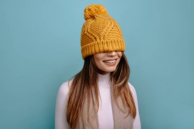 Komik, pozitif kadın portresi, şapkası gözlerinde, gülümsüyor.