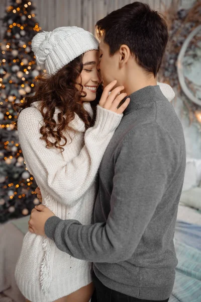 Güzel, genç bir çift Noel ağacının yanında dikilip Noel 'i evde kutluyor..