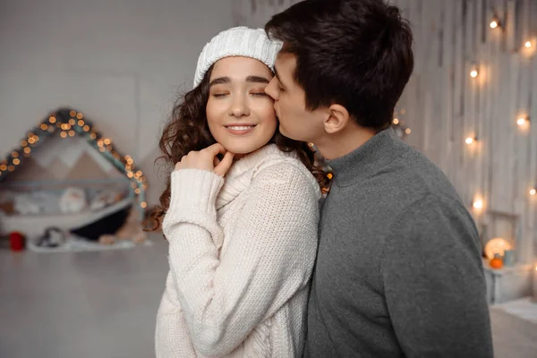 Ung kille kysser sin vackra flickvän känner lycka samtidigt fira vinter semester tillsammans Royaltyfria Stockbilder