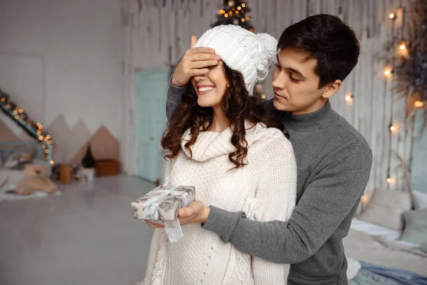 Mannen håller sina flickväns ögon täckta medan han ger en present, romantisk överraskning till jul Stockbild