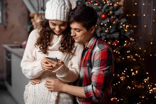 Mutlu genç çift akıllı telefondan Noel mesajlarını kontrol ediyor. 