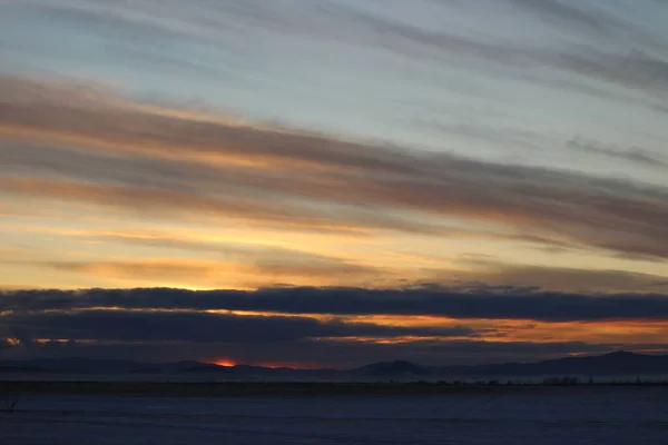 Gün batımının canlı renkleri Gökyüzü ve Kırmızı Turuncu Sarı Bulutlar. Kış Manzarası Görünümü ve Karlı Dağlar 