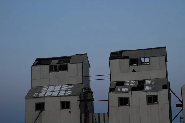 Terk edilmiş sanayi binalarının kalıntıları. Gün batımında berrak gökyüzü olan tarım tahıl ambarı. 