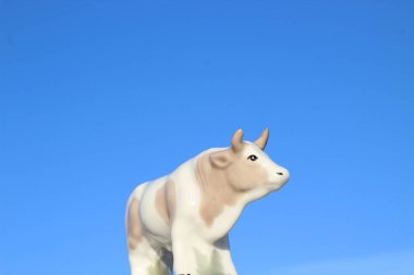 Ay takviminde 2021 Yılının Küçük Boğa Heykeli Sembolü. Açık Mavi Gökyüzüne karşı Boynuzlu Beyaz Benekli İnek Heykeli