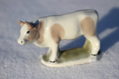 Ay takviminde 2021 Yılının Küçük Boğa Heykeli Sembolü. Boynuzlu Beyaz Benekli İnek Kışın Beyaz Kar Üzerinde 