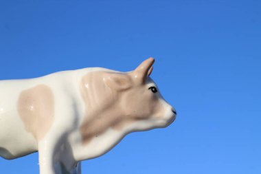 Ay takviminde 2021 Yılının Küçük Boğa Heykeli Sembolü. Açık Mavi Gökyüzüne karşı Boynuzlu Beyaz Benekli İnek Heykeli