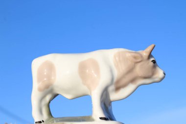 Ay takviminde 2021 Yılının Küçük Boğa Heykeli Sembolü. Açık Mavi Gökyüzüne karşı Boynuzlu Beyaz Benekli İnek Heykeli