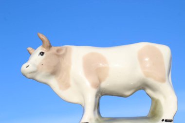 Ay takviminde 2021 Yılının Küçük Boğa Heykeli Sembolü. Açık Mavi Gökyüzüne karşı Boynuzlu Beyaz Benekli İnek Heykeli