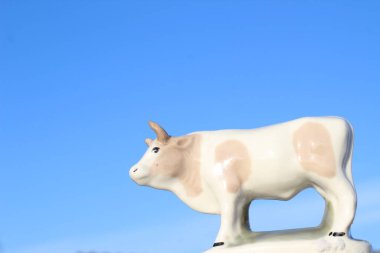 Ay takviminde 2021 Yılının Küçük Boğa Heykeli Sembolü. Açık Mavi Gökyüzüne karşı Boynuzlu Beyaz Benekli İnek Heykeli