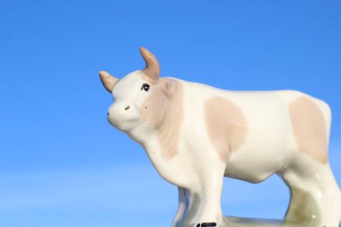 Ay takviminde 2021 Yılının Küçük Boğa Heykeli Sembolü. Açık Mavi Gökyüzüne karşı Boynuzlu Beyaz Benekli İnek Heykeli