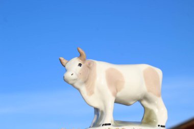 Ay takviminde 2021 Yılının Küçük Boğa Heykeli Sembolü. Açık Mavi Gökyüzüne karşı Boynuzlu Beyaz Benekli İnek Heykeli