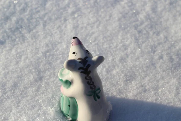 Mouse Symbol of Lunar Calendar Little Porcelain Figurine in Winter Snow. Small Statuettes of Cute Rat Holding Bag Full of Wealth and Health