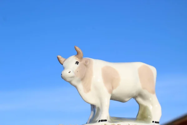 Ay takviminde 2021 Yılının Küçük Boğa Heykeli Sembolü. Açık Mavi Gökyüzüne karşı Boynuzlu Beyaz Benekli İnek Heykeli