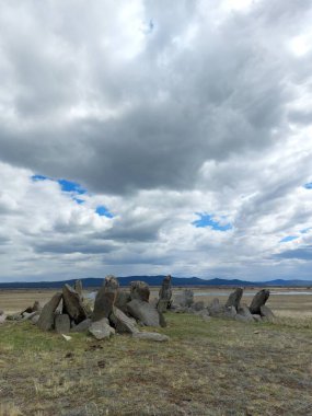 Mavi bulutlu gökyüzünün altındaki antik mezar taşları. Rus Uzak Doğu