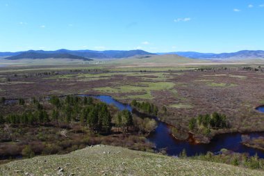 Nehir vadiyi ve ormanı geçerken Mavi Gök 'ün altındaki hava manzarası su yüzeyini ve ufuktaki dağları yansıtıyor. 
