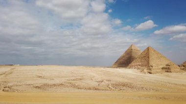 Büyüleyici Giza piramitlerini keşfedin Mısırları gösteren tarihi piramitleri mavi gökyüzü altında bulutlu bir günde, büyüleyici fotoğraf ve keşif için mükemmel bir zemin sunarak.