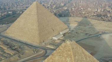 Giza, Mısır 'daki Khufu ve Khafre piramitlerinin hava manzarası ihtişamlarını sergiliyor. Kamera, engin çöl manzarasına karşı kurulmuş görkemli yapıları gözler önüne sermek için eğiliyor..