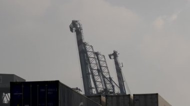 Port Said, Mısır - 7 Aralık 2020: Çeşitli nakliye konteynırları Port Said limanında, deniz ticareti ve taşımacılığı için hayati önem taşıyan etkin lojistik ve operasyonları gösteren bir gantry vinç ile birlikte istiflenmiştir..