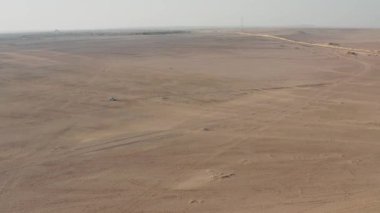 Çölde kumlu bir arazide araba sürerken çekilen hava görüntüsü. Güzel çöl manzarasını canlı renklerle gezen arabanın çarpıcı hava manzarasını deneyin..