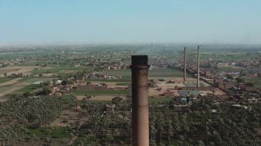 Havadan bakıldığında, eski bir tuğla fabrikasını aydınlatan büyük tarihi bir baca veya boru görülüyor. Bu sanayi simgesi, şehrin üretim mirasının bir kanıtı olarak duruyor..