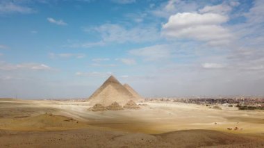 Mısır 'daki Giza piramitlerinin büyüleyici manzarasını keşfedin. Bu ikonik piramitlerin tarihsel önemini, mavi gökyüzü ve dağınık bulutlara karşı deneyimleyin..