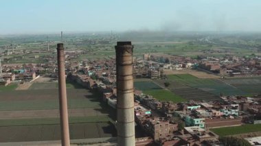 Hava görüntüsünde eski bir tuğla fabrikasının yanındaki eski büyük bir boru ya da baca görünüyor. Bu resim kentsel ortamlardaki tarihi endüstriyel mimariyi vurgular.