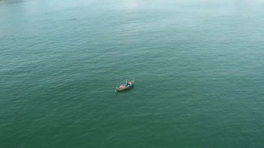 Küçük bir balıkçı teknesinde, sakin sularda yüzen yalnız bir balıkçının hava perspektifi, sakin ve uzak bir yerde doğanın güzelliğini ve balıkçılık sanatını gözler önüne seriyor..